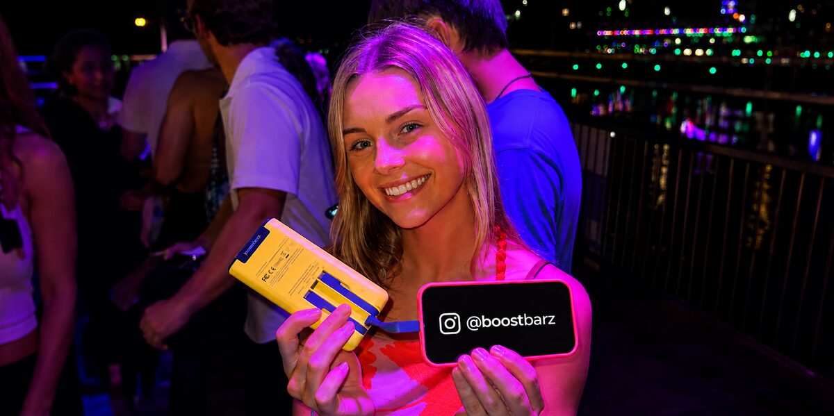 Guest holding a BoostBarz power bank at a night event